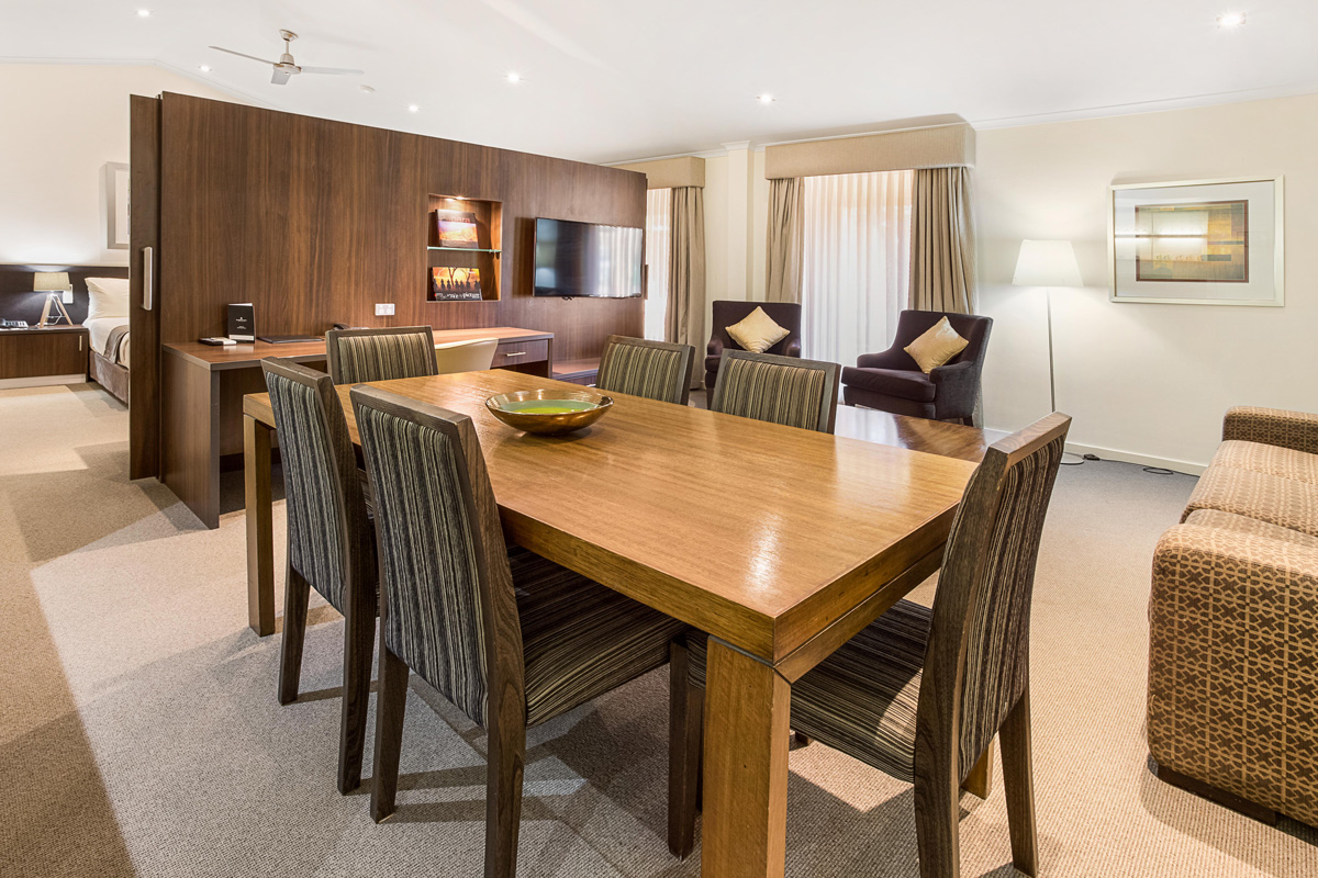 The Presidential Suite includes a spacious living and dining area with a table and 6 chairs, a sofa and sofa chairs, and two TVs