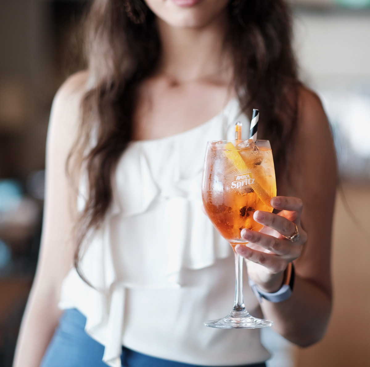 A hotel guest holds a glass of aperol spritz