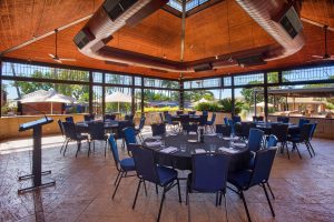 The Conservatory function area is equipped with round tables and chairs, drinking glasses, writing stationery, and a podium for speakers