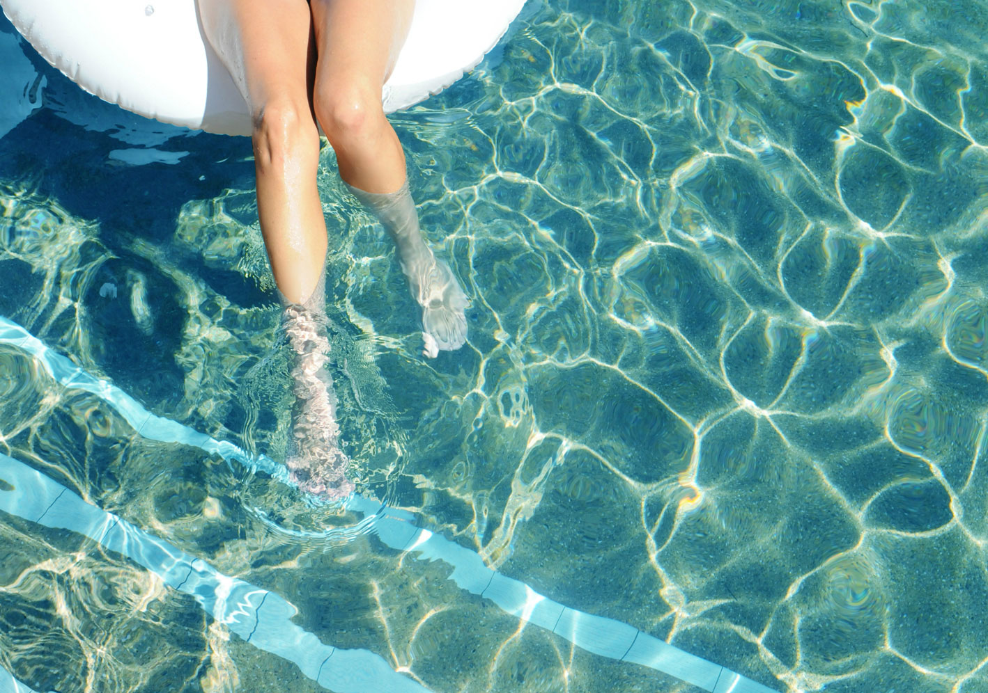 A hotel guest dangles their feet in the pool at the Karratha International Hotel