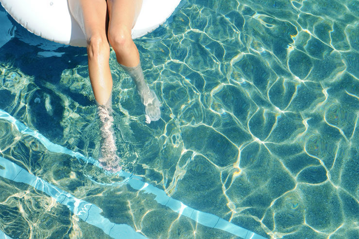 A hotel guest dangles their feet in the pool at the Karratha International Hotel