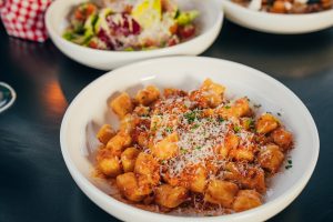 A plate of gnocchi pasta with a meat and tomato-based sauce