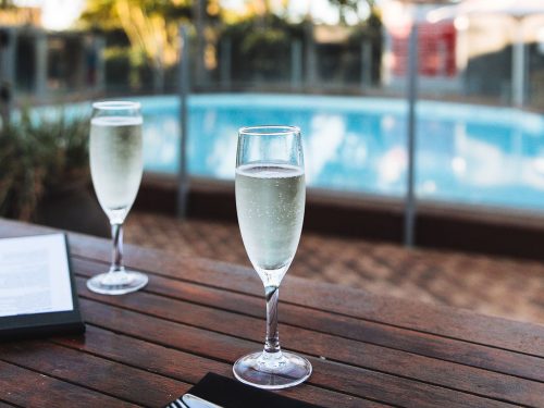 Two champagne glasses by the poolside