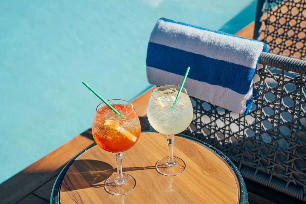 Two cocktails sitting on the table by the poolside.