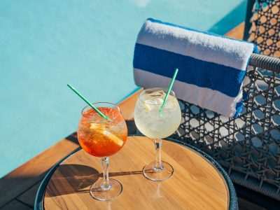 Two cocktails sitting on the table by the poolside.